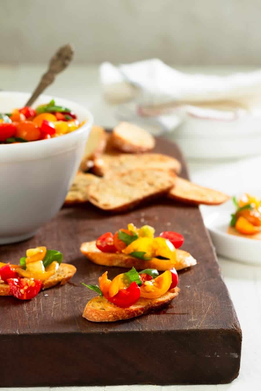 crostini topped with bruschetta on a wood board.