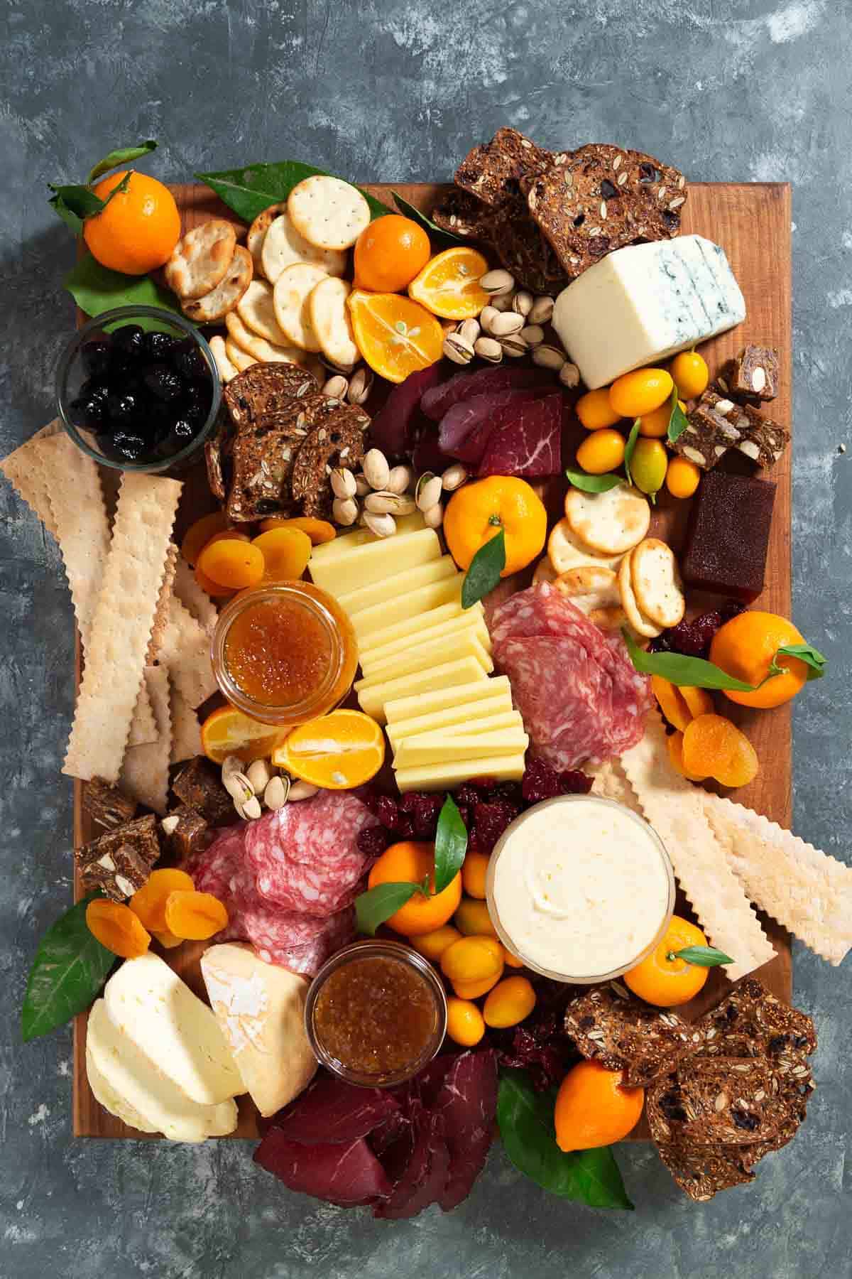 crackers, meat, cheese, jams, nuts, dried fruit on a large wooden cutting board