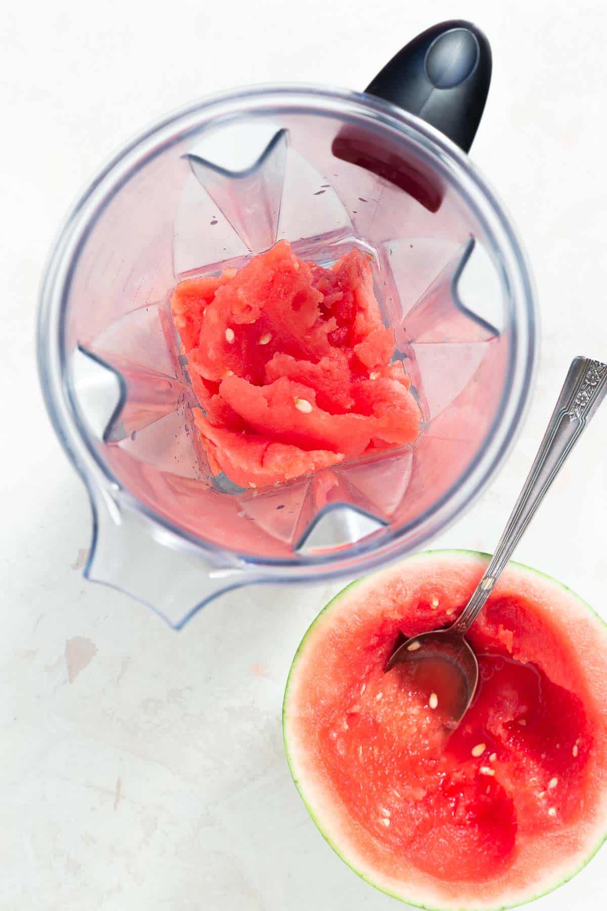 Overhead view of a scooped out watermelon with the fruit in a blender