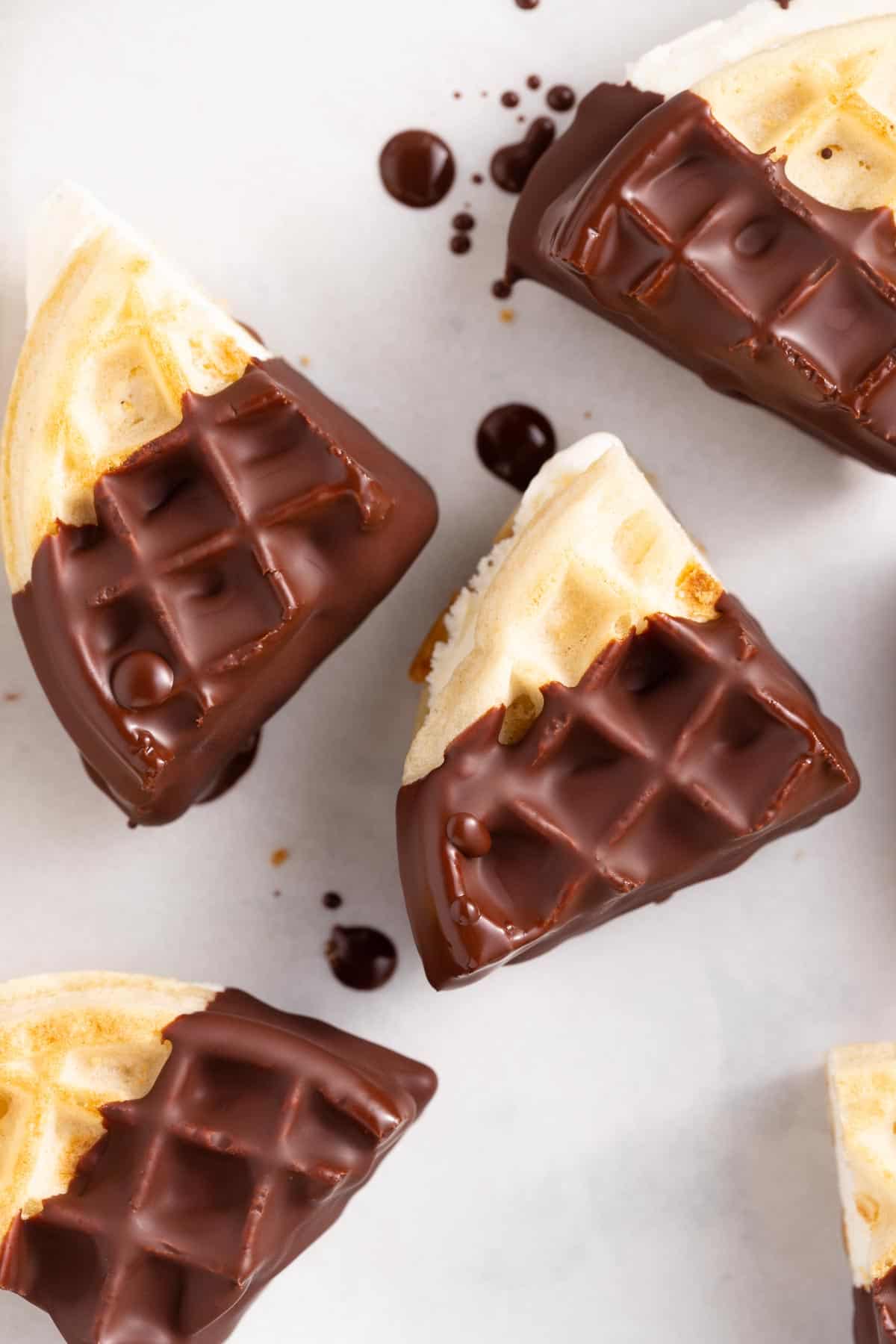 close up on chocolate dipped waffle ice cream sandwiches on parchment paper