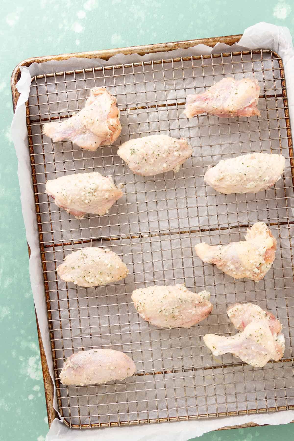 rows of raw chicken wings on a wire rack.