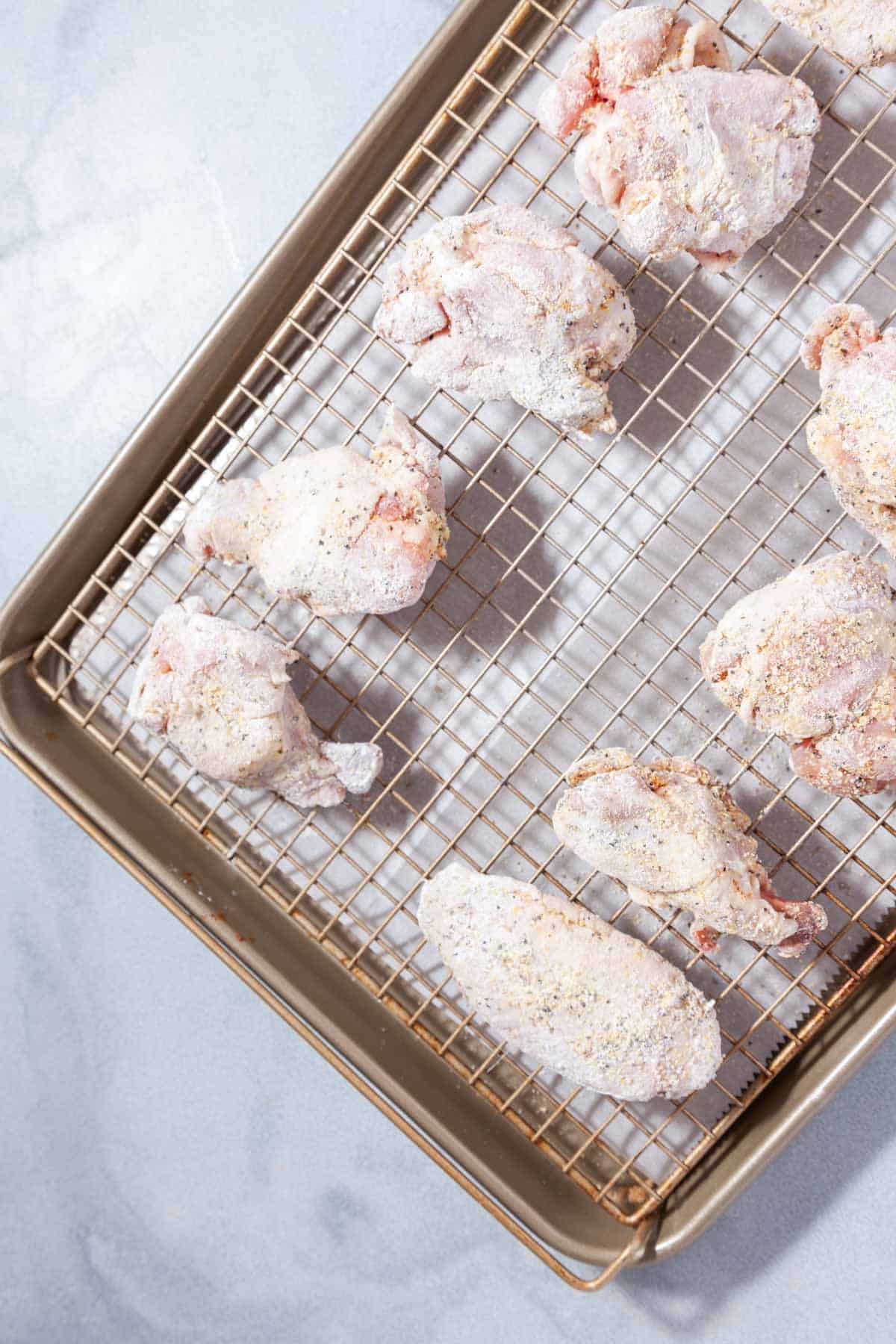 rows of raw chicken wings on a wire rack.