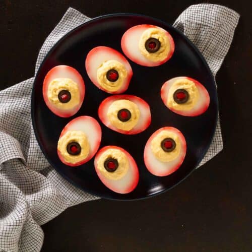eyeball deviled eggs on a black plate.
