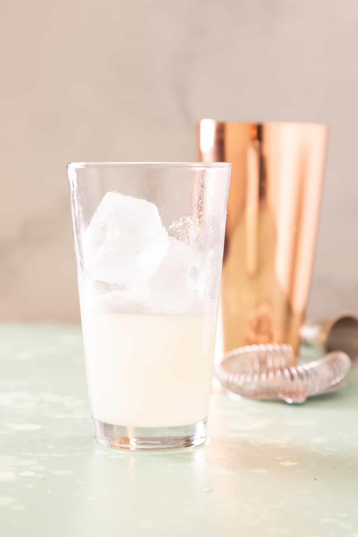 A tall glass filled with a translucent white liquid and ice in it.