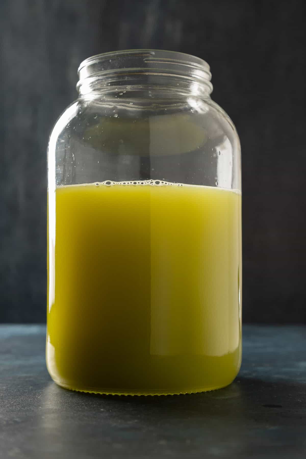 A large glass punch jar filled with a muddy green colored liquid.
