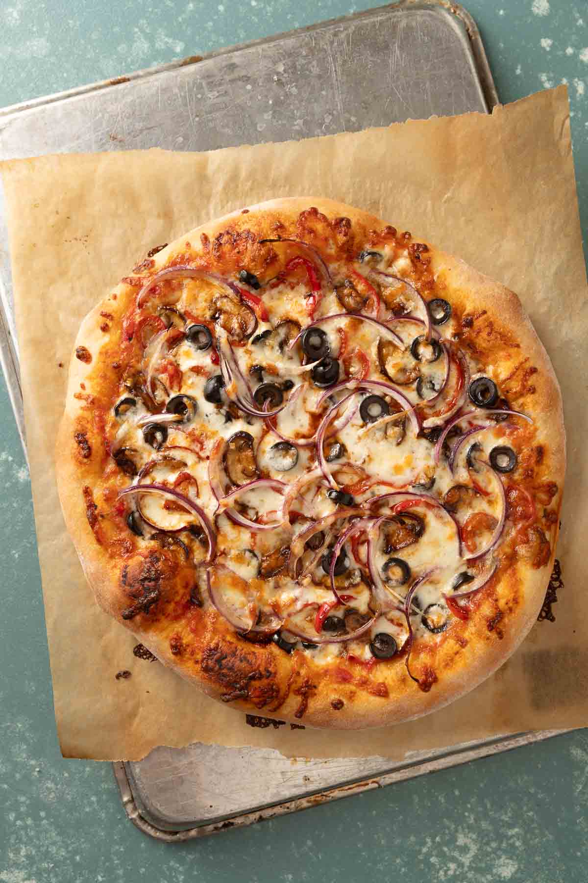 Overhead of a whole pizza on a baking sheet topped with lots of veggies.