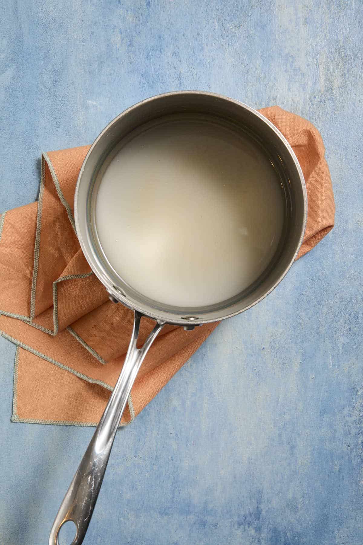 Overhead image of a saucepan with sugar and water mixed together in it.