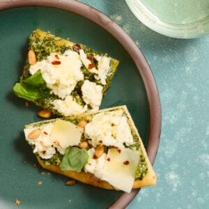 Two small pieces of pesto and mozzarella flatbread on a small plate.