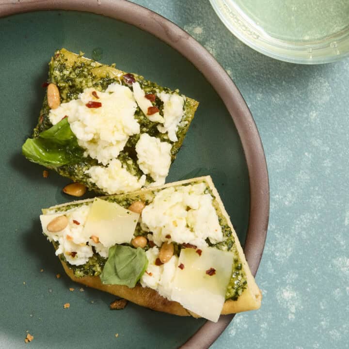Two small pieces of pesto and mozzarella flatbread on a small plate.
