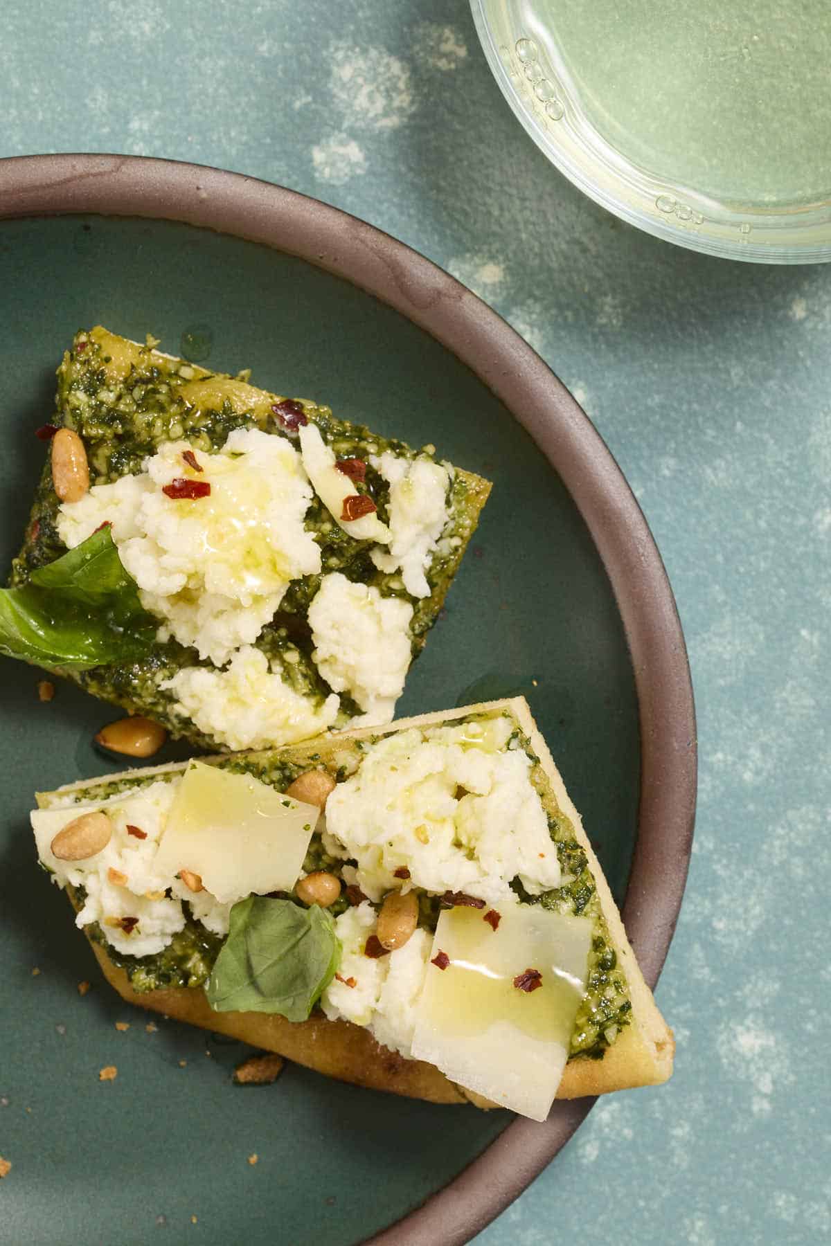 Two small pieces of pesto and mozzarella flatbread on a small plate.